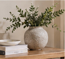 Illustrative textured vase and leafy stems in a quiet interior